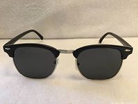Front view of sunglasses showing black upper frame, metal lower rims, dark lenses
