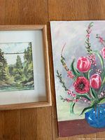 Both paintings side by side: framed watercolor landscape and unframed floral on board