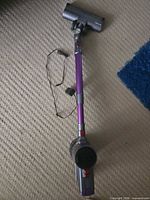 Full stick vacuum assembled with charger cord alongside