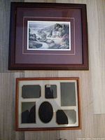 Dark brown wood framed landscape print and light wood collage frame laid on floor
