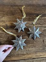 Three pierced tin star ornaments on wooden surface showing size and overall appearance