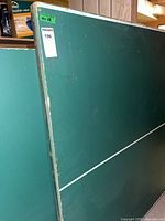 Side view of green ping pong table showing playing surface and edge wear