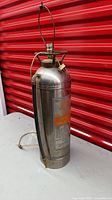 Full view of converted fire extinguisher lamp showing stainless body, hose, harp