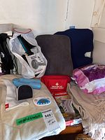 Overview of lot showing weighted blanket, cushions, first aid kit, Tensor boxes, Poise pads, blue back stretcher, digital device