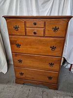 Front view showing all five drawers, hardware, finish and overall style