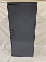 Front view of gray steel cabinet showing single hinged door and handle