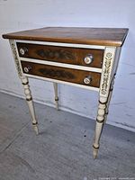 Front view showing two drawers, turned legs, stenciling, knobs