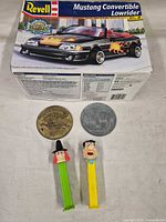 Front view of all items: Revell model kit box, two large coins, two PEZ dispensers