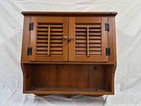Front view of wall cabinet showing louvered doors and open shelf