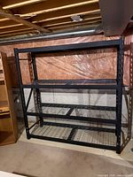 Front view of entire black metal rack showing four wire shelves