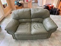 Front view of sage green faux leather loveseat