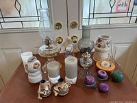 Full lot overview showing oil lamps, candles, holders and decorative pieces on table