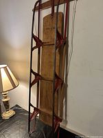 Full vertical view of sled front showing wood deck, red steel runners and pull rope