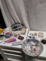 Overall view of supplies on work surface including pouch, cord spools, wire, findings bowl
