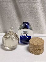 Two glass paperweights (clear with waved top, clear with blue swirl) and stone trinket box