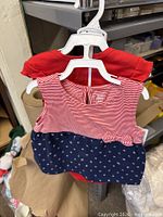 Front view of one complete outfit on hanger showing dress over bodysuit