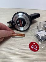 Label maker showing character wheel and installed wood-grain tape, sample embossed label visible