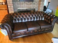 Full front view of brown leather Chesterfield sofa
