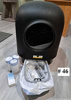 Front view of black automatic litter box with open entry, waste drawer, scoop, power adapter and four rolls of bags