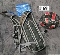 Rear view of High Sierra hydration backpack showing padded straps, attached hose and blue water bladder, alongside deflated black and red soccer ball