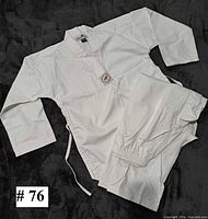 Judo jacket, pants and belt laid out on dark background