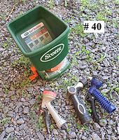 Top view of green Scotts hand-crank spreader with three assorted hose nozzles on gravel surface