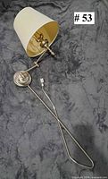 Full view of brushed silver swing arm wall lamp with off-white shade and mounting plate