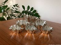 Six shiny, fluted molds stacked on wooden surface