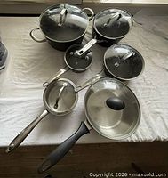 All six pans with their lids arranged on table