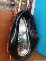 Front view of leather horse collar mirror showing overall design and red/orange hardware