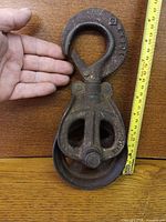 Front view of cast iron pulley beside measuring tape showing 10 in length