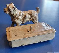 Dog figurine attached to trinket box showing missing leg and lid inscription