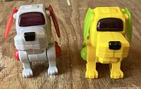 Front view of both robotic dogs, grey/red and yellow/green