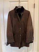 Front view of dark brown suede shearling coat on hanger