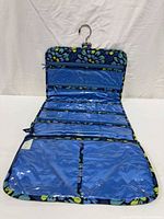 Organizer fully opened showing metal hook, zippered vinyl pockets and blue floral exterior border