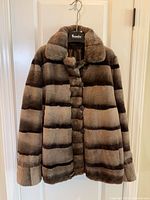Front view of reversible fur coat on hanger showing button front, collar, striped pattern