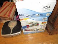 Photo of SpaceBags vacuum seal storage bag set in original box alongside striped woven bag and scale.