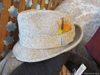 Close-up of herringbone patterned wool hat with orange and yellow feather decoration