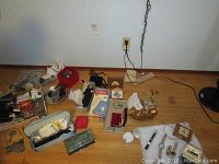 Overview photo of lot with watches, pens, gloves, small boxes, and purse spread on floor