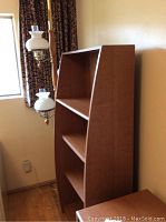 Medium brown wood finish bookcase with three open shelves and angled sides, Sauder Library style.