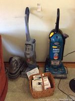 Photo shows three vacuum cleaners: blue Eureka upright, grey Hoover FloorMate, and grey Bissell SpotBot carpet cleaner. Basket with vacuum bags and filters in front.