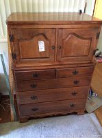 Front view of wooden chest showing doors on upper section, drawers below, and wood finish.