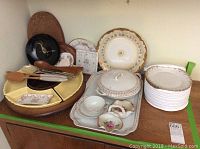 Full view of serving dishes including plates, floral ceramic trays, covered serving dish, wooden spoons and utensils on top of yellow ceramic lazy Susan