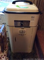 Front view of the vintage Hamilton Beach automatic roaster oven, showing cream-colored body, control knob, lower cabinet with door, and handle on lid.