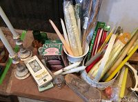 Candles including boxed tealights, taper candles in different colors, green glass votive holders, two Scentpot containers in original box, metal candlesticks, and wooden metal shoe form.
