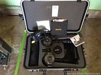 Open hard protective case containing the SeaLife underwater camera mounted on a handle with attached circular LED lighting, floating hand grip, memory card case, cleaning cloth, and manual.