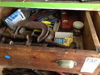 Top view of wooden drawer containing clamps, hand files, small containers, and assorted tools and hardware.