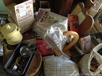 View of Insta-hot yellow kettle, baking pans, clothespins, cheesecloth bag, and laundry hamper on a table.