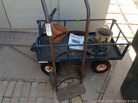Photo showing entire Tricam garden cart with mesh sides, hand truck in front, two terra cotta plant pots inside the cart, and garden trivet.