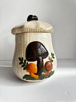 Front view of ceramic mushroom storage jar showing relief mushrooms and lid design